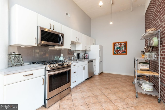 kitchen with tasteful backsplash, stainless steel appliances, a high ceiling, and white cabinets