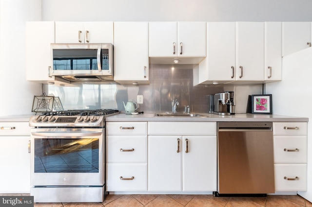 kitchen featuring sink, light tile patterned floors, white cabinets, stainless steel appliances, and backsplash