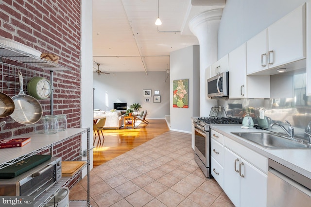 kitchen featuring sink, ceiling fan, appliances with stainless steel finishes, white cabinetry, and light tile patterned flooring