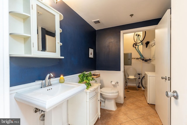 bathroom featuring tile patterned flooring, sink, washer and dryer, and toilet