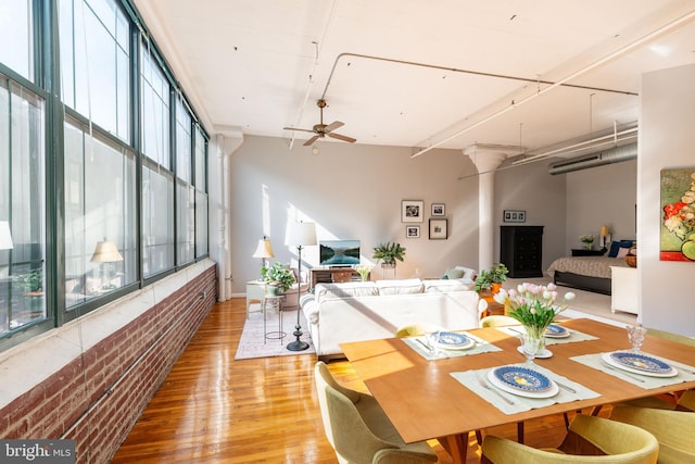 dining area with hardwood / wood-style flooring, a wall of windows, ceiling fan, and decorative columns