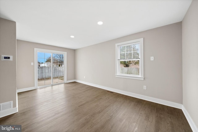 spare room with plenty of natural light and dark hardwood / wood-style floors