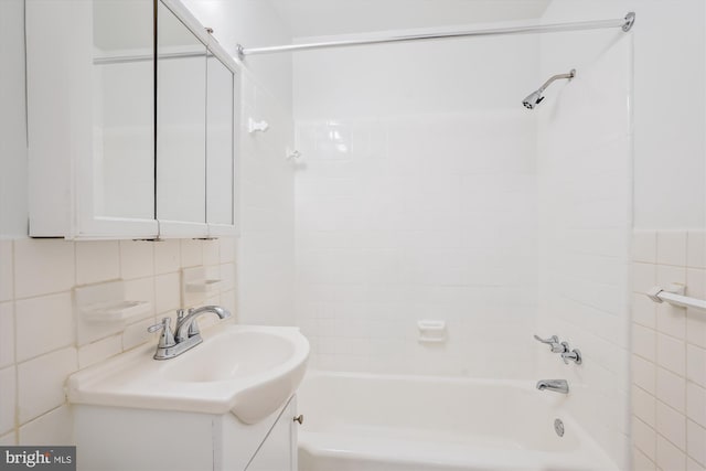 bathroom with tile walls, vanity, and tiled shower / bath combo