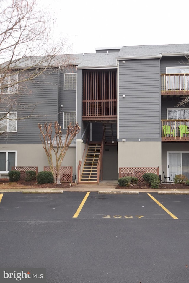 view of building exterior with stairs and uncovered parking