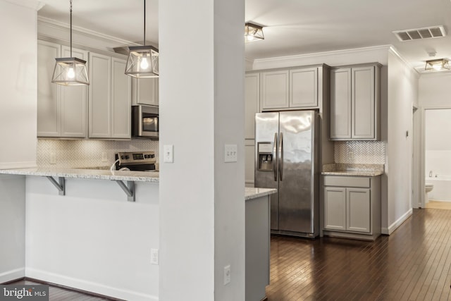 kitchen with appliances with stainless steel finishes, a breakfast bar, pendant lighting, and gray cabinetry