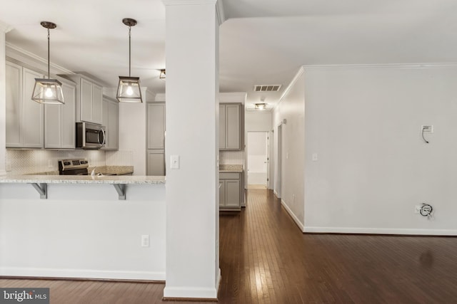 kitchen with pendant lighting, gray cabinets, a breakfast bar, and appliances with stainless steel finishes