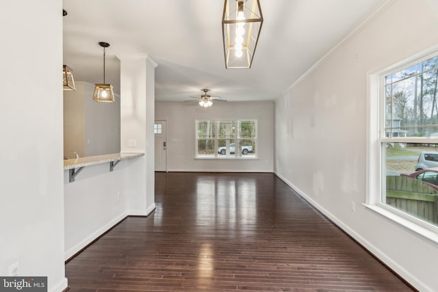 unfurnished living room featuring crown molding, plenty of natural light, ceiling fan, and dark hardwood / wood-style flooring