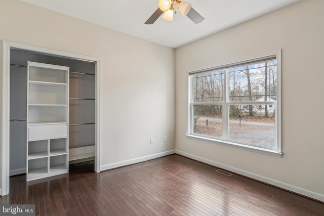 unfurnished bedroom featuring dark wood-type flooring, ceiling fan, and a closet