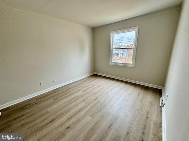 spare room with ornamental molding and light wood-type flooring