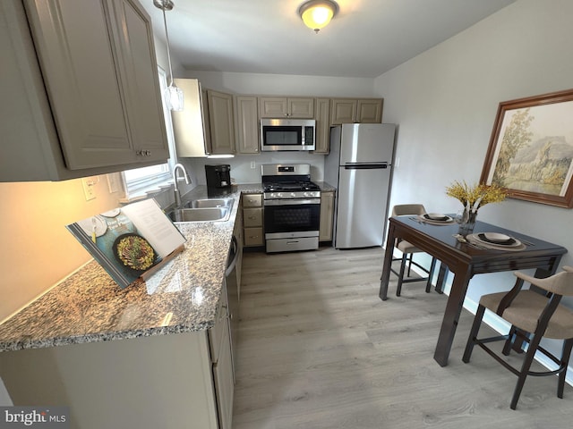 kitchen featuring sink, gray cabinetry, light stone counters, hanging light fixtures, and appliances with stainless steel finishes