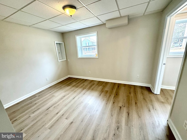 empty room with a drop ceiling and light wood-type flooring