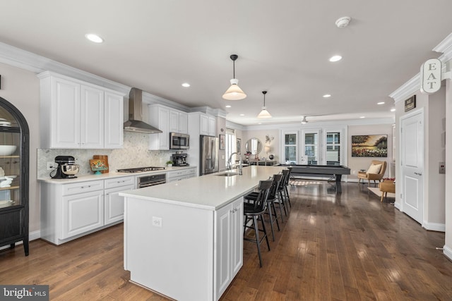 kitchen featuring a kitchen bar, sink, decorative light fixtures, stainless steel appliances, and white cabinets