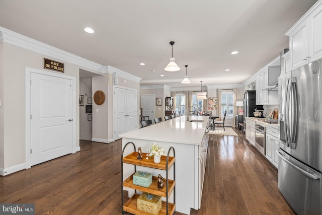 kitchen featuring appliances with stainless steel finishes, decorative light fixtures, white cabinetry, an island with sink, and dark wood-type flooring