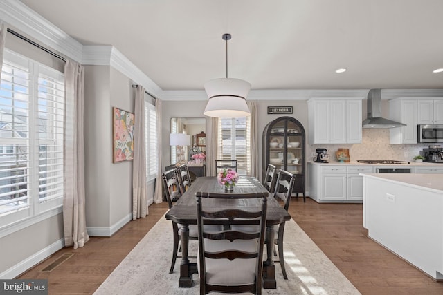 dining room with crown molding and light hardwood / wood-style floors