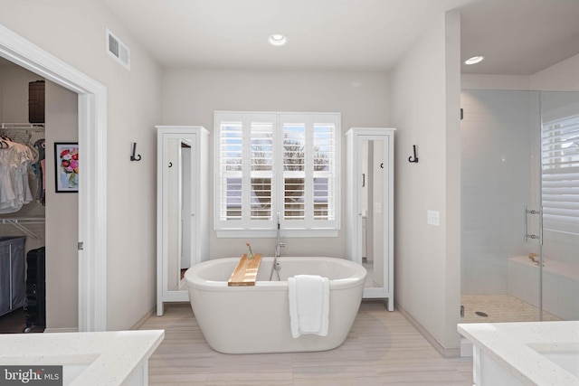 bathroom featuring vanity, separate shower and tub, and hardwood / wood-style floors