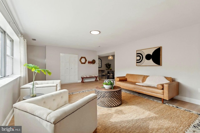 living room with wood finished floors, visible vents, and baseboards