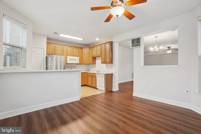 kitchen featuring ceiling fan with notable chandelier, white appliances, light hardwood / wood-style floors, and hanging light fixtures