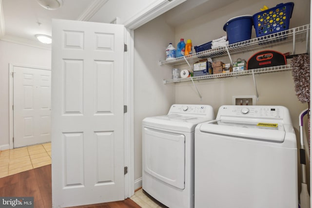 laundry room with crown molding, wood-type flooring, and washing machine and clothes dryer