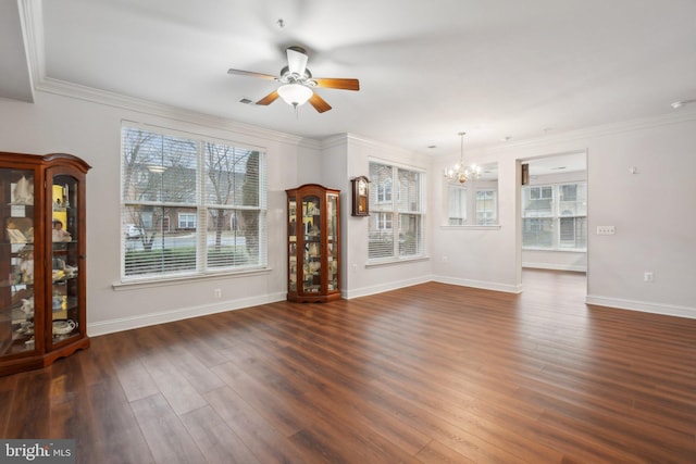 unfurnished living room with dark hardwood / wood-style flooring, crown molding, ceiling fan with notable chandelier, and a healthy amount of sunlight