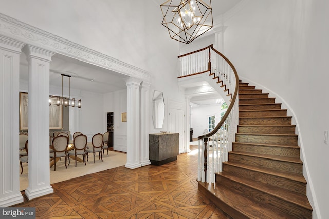 foyer entrance featuring a chandelier, stairway, a towering ceiling, and ornate columns