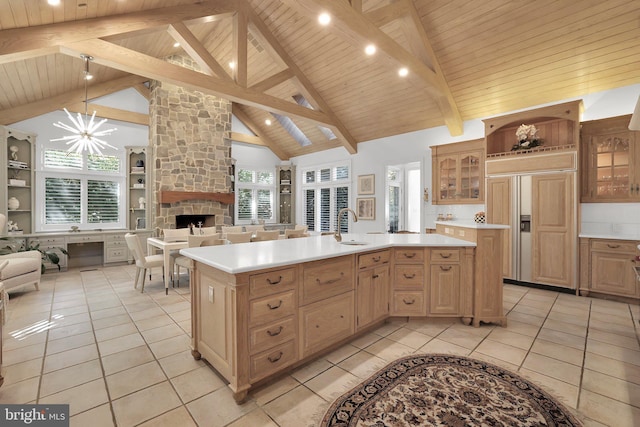 kitchen with paneled fridge, a kitchen island with sink, open floor plan, light countertops, and glass insert cabinets