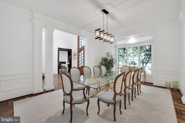 dining room featuring ornamental molding, wainscoting, decorative columns, and a decorative wall