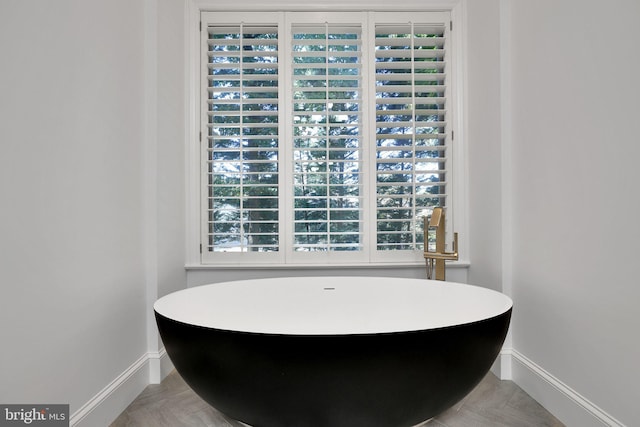 bathroom featuring a freestanding tub and baseboards