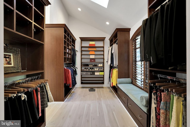 spacious closet featuring lofted ceiling with skylight and light wood-style flooring