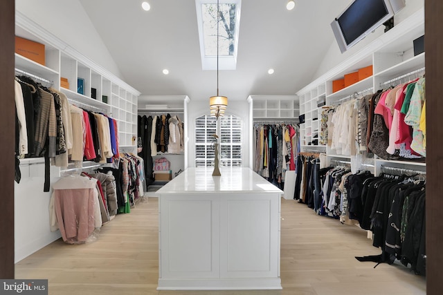 walk in closet featuring vaulted ceiling with skylight and light wood-style flooring