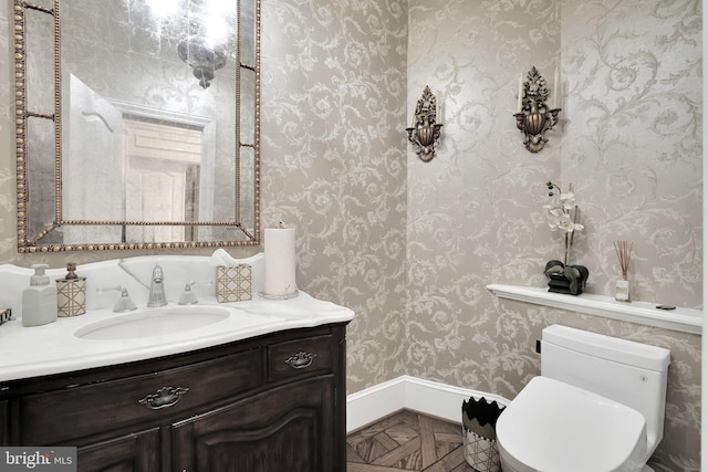 bathroom featuring vanity, toilet, and wallpapered walls