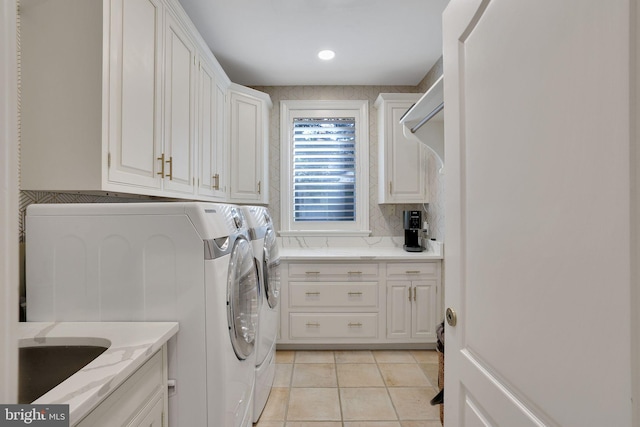 clothes washing area with cabinet space, light tile patterned floors, and separate washer and dryer