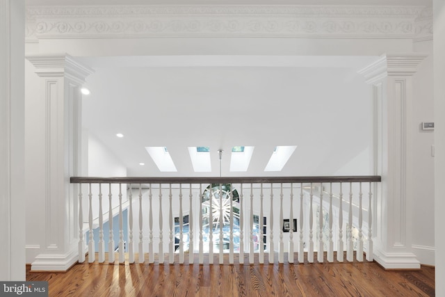 corridor with a skylight, wood finished floors, and decorative columns