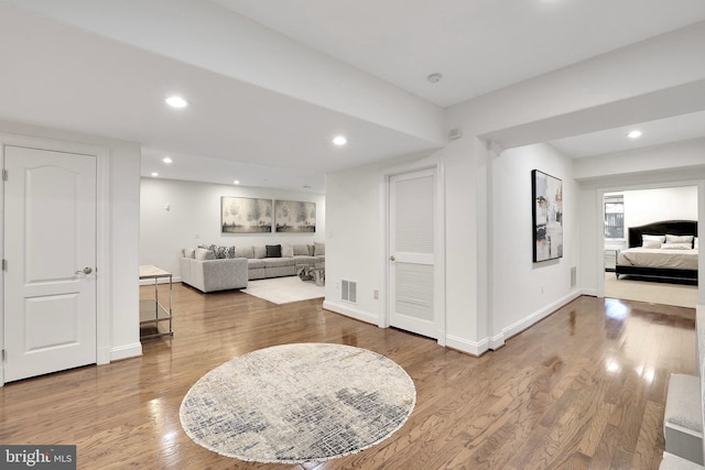 living area with baseboards, wood finished floors, visible vents, and recessed lighting