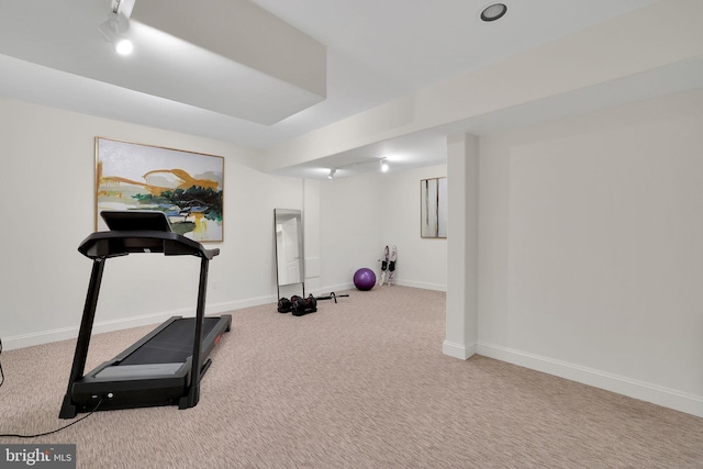 exercise area featuring light colored carpet and baseboards