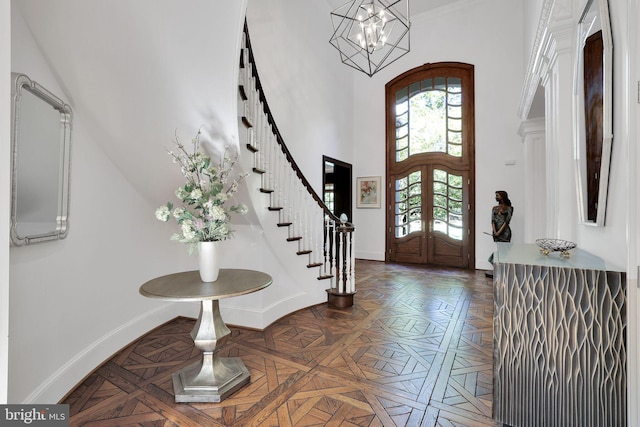 foyer entrance with french doors, a high ceiling, an inviting chandelier, baseboards, and stairs