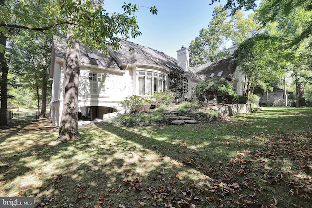 exterior space featuring a chimney, fence, and a yard