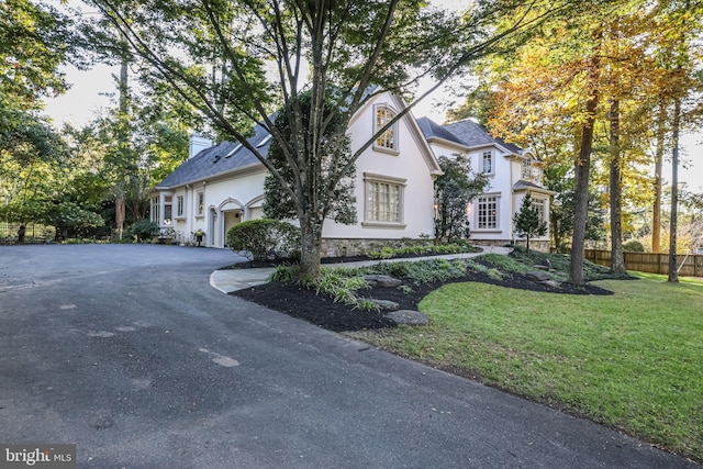 view of front of house featuring stucco siding, an attached garage, fence, driveway, and a front lawn