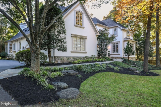 view of front of home with stone siding, a front yard, and stucco siding