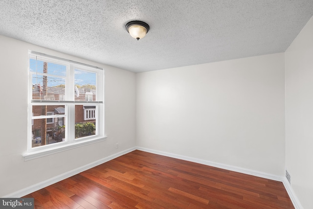 spare room with dark hardwood / wood-style floors and a textured ceiling