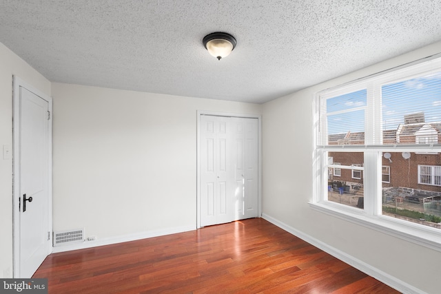 unfurnished bedroom with hardwood / wood-style flooring, a closet, and a textured ceiling