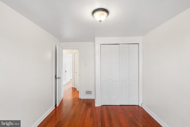 unfurnished bedroom with a closet and dark hardwood / wood-style floors