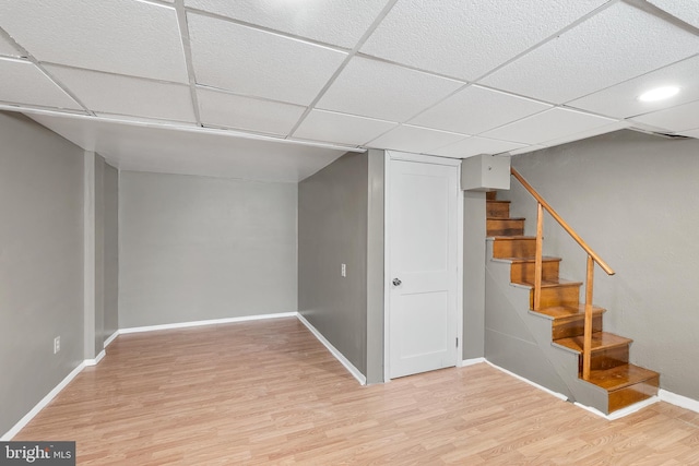 basement with a drop ceiling and light hardwood / wood-style floors