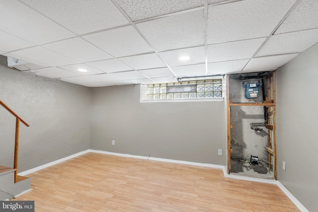 basement featuring a paneled ceiling and hardwood / wood-style floors