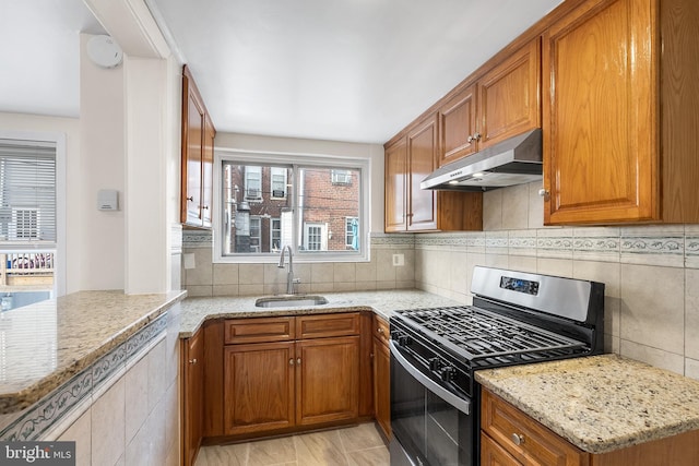 kitchen featuring light stone counters, sink, decorative backsplash, and stainless steel range with gas cooktop