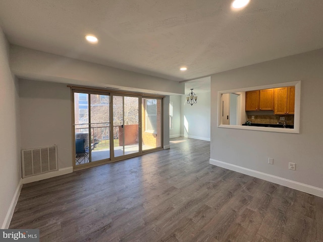 spare room featuring hardwood / wood-style flooring, a notable chandelier, and a textured ceiling