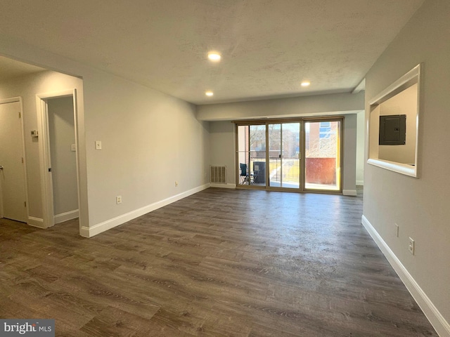 spare room featuring dark wood-type flooring, electric panel, and a textured ceiling