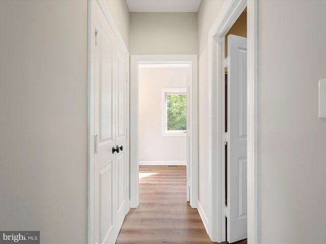 corridor featuring baseboards and wood finished floors