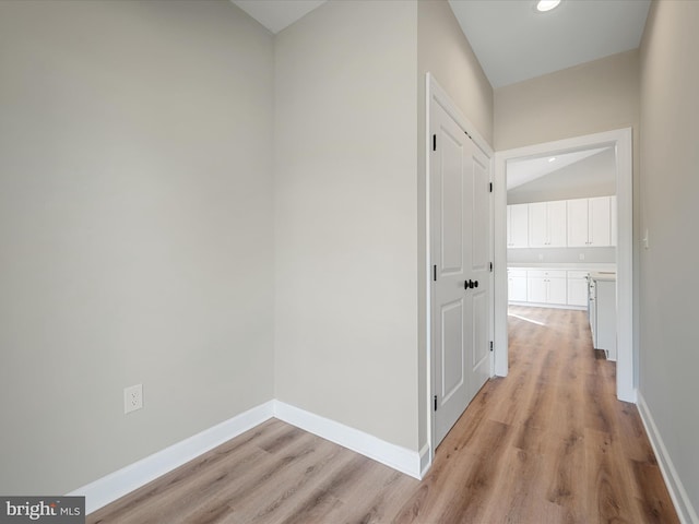 hallway featuring recessed lighting, baseboards, lofted ceiling, and light wood-style floors