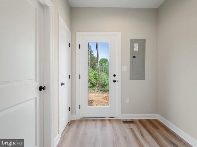 doorway featuring light wood-style floors, baseboards, electric panel, and visible vents