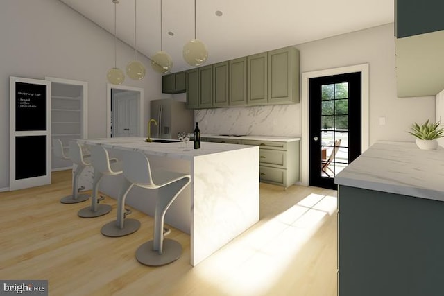 kitchen with a breakfast bar, light wood-style floors, a center island with sink, stainless steel refrigerator with ice dispenser, and backsplash